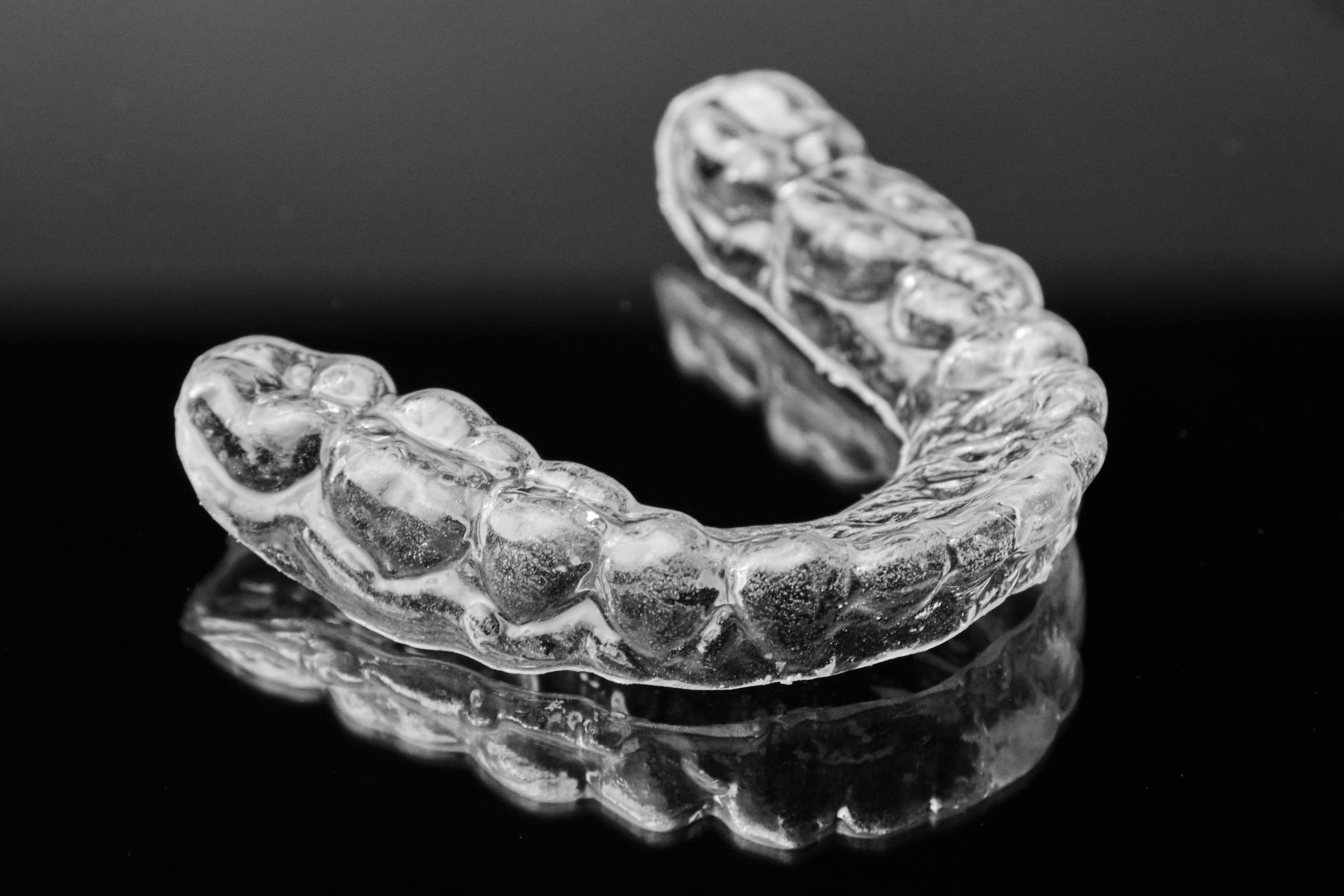 Invisible transparent dental removable braces on the black background. Orthodontic appliance for dental correction. Aligners for teeth straightening
